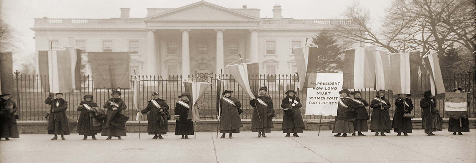 A historical stock photo of women suffragists protesting outside of the White House.